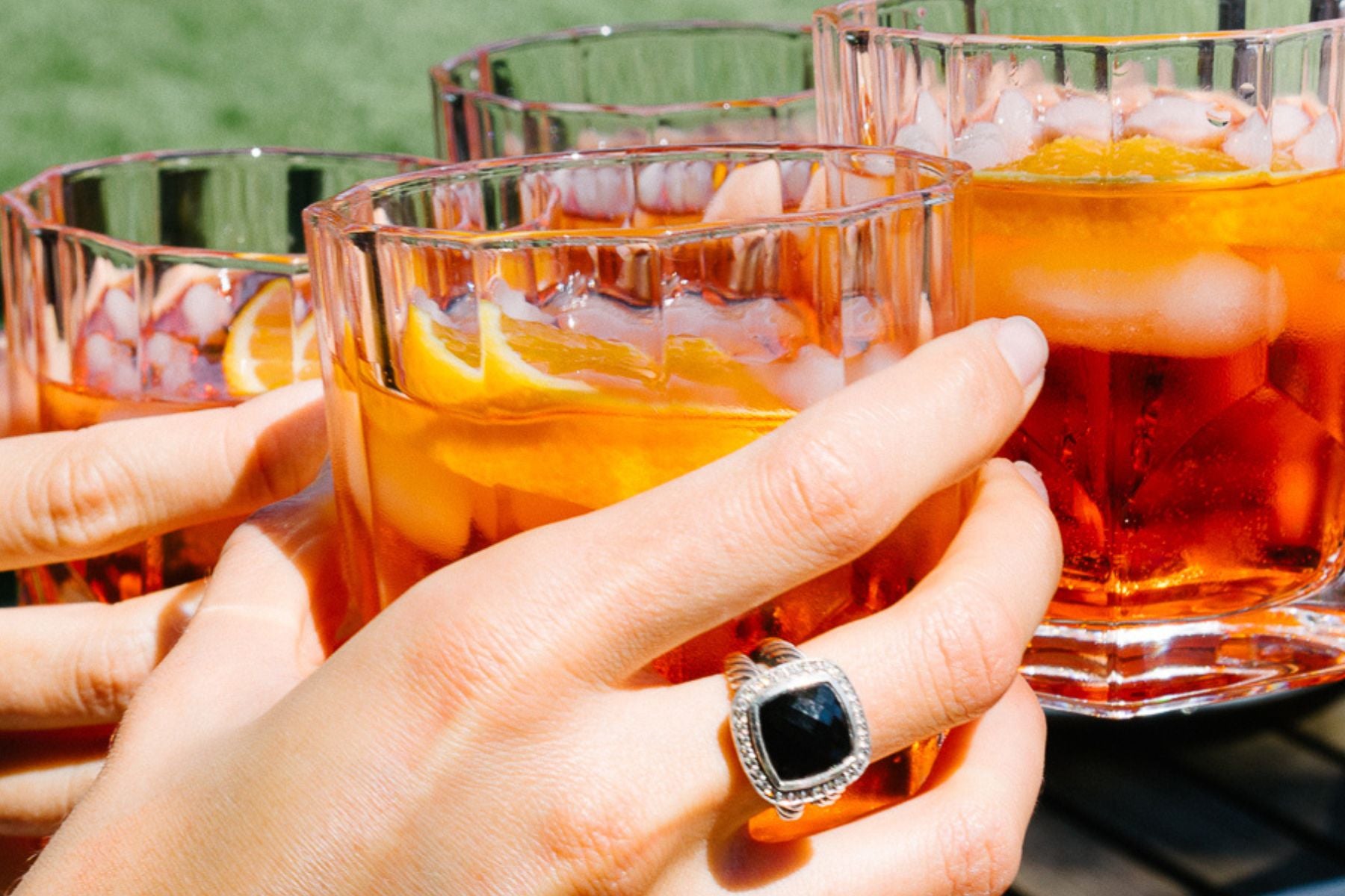 Refreshing Aperol Spritz cocktails with orange slices, served over ice in crystal glasses at an outdoor summer event in Shenton Park. A relaxed alfresco dining experience at Wholefood Circus.